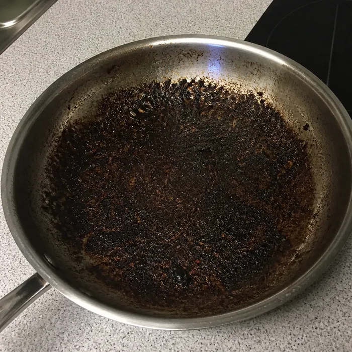 Stainless steel pan with heavy burnt-on residue before cleaning
