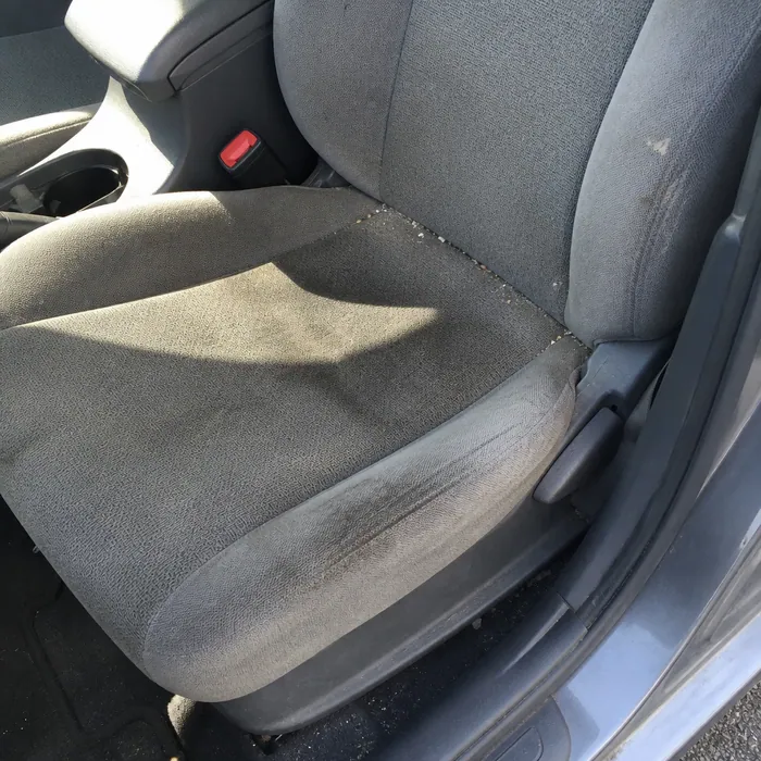 Grey cloth car seat with ground-in grime before cleaning